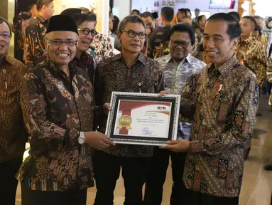 Presiden Jokowi menerima penghargaan sebagai pelapor gratifikasi dengan nilai terbesar yang ditetapkan menjadi milik negara dari Ketua KPK, Agus Rahardjo pada peringatan hari Antikorupsi Dunia, Jakarta, Senin (11/12). (Liputan6.com/Angga Yuniar)
