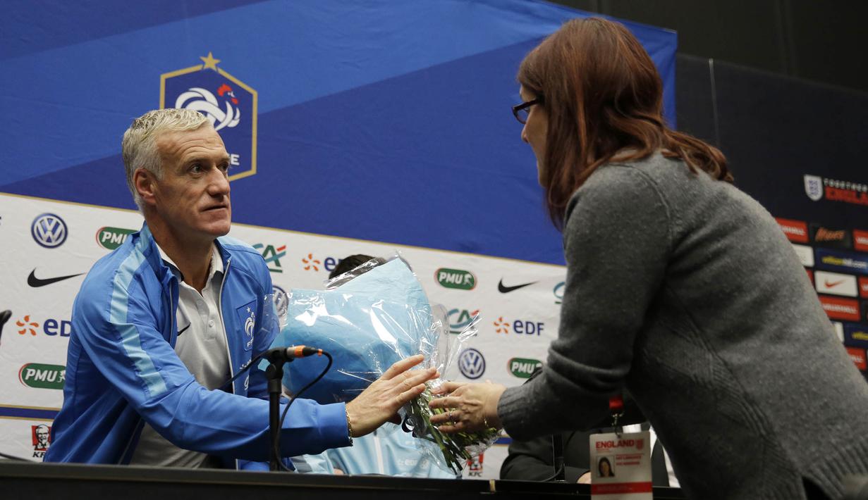 Pelatih Prancis, Didier Deschamps menerima bunga dari seorang jurnalis sebagai tanda berduka cita saat jumpa pers di Inggris, Senin (16/11/2015). (Action Images via Reuters/Henry Browne)