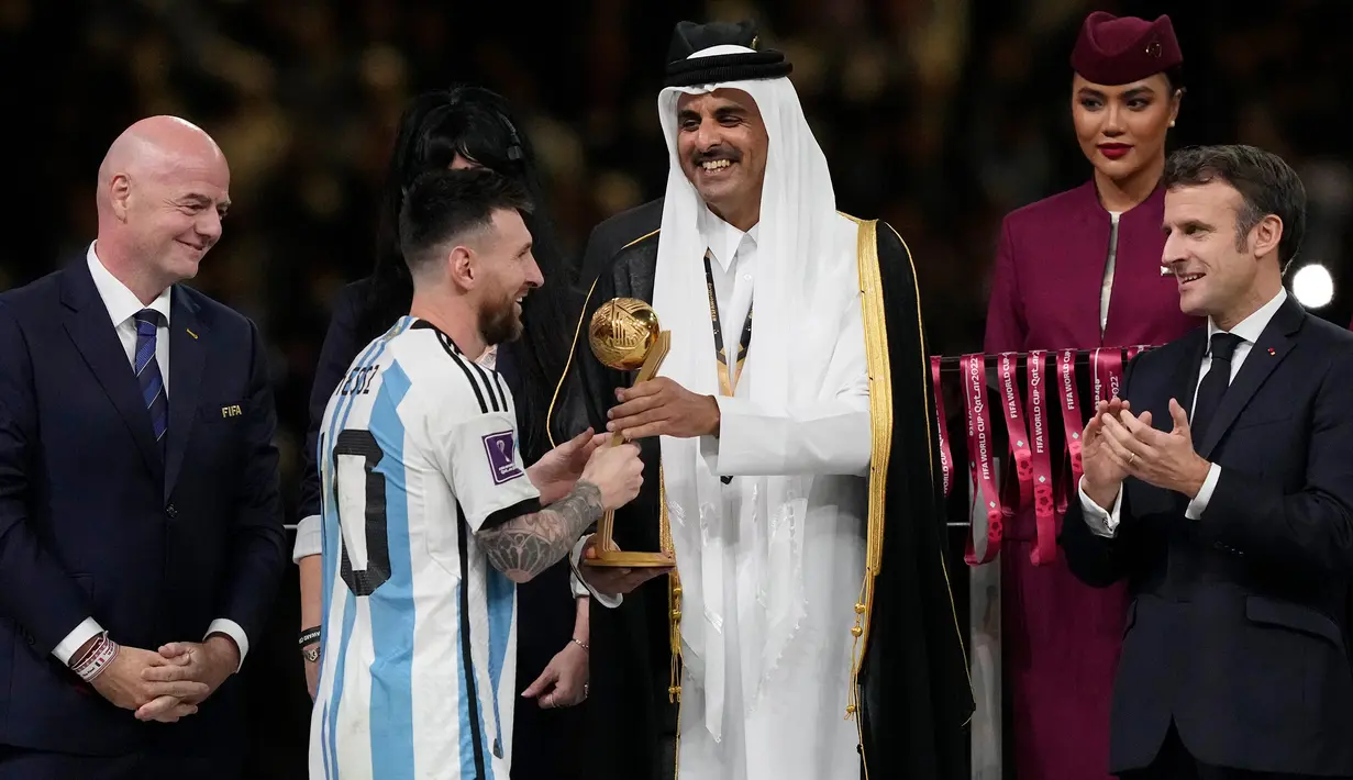 Emir Qatar Sheikh Tamim bin Hamad Al Thani menyerahkan penghargaan Bola Emas kepada Lionel Messi sementara Presiden Prancis Emmanuel Macron (kanan) bertepuk tangan pada akhir pertandingan sepak bola final Piala Dunia 2022 antara Argentina dan Prancis di Stadion Lusail, Lusail, Qatar, 18 Desember 2022. Lionel Messi dinobatkan sebagai peraih Bola Emas atau Golden Ball sebagai perlambang pemain terbaik selama Piala Dunia 2022 setelah memimpin Argentina menaklukkan Prancis dalam babak final. (AP Photo/Martin Meissner)