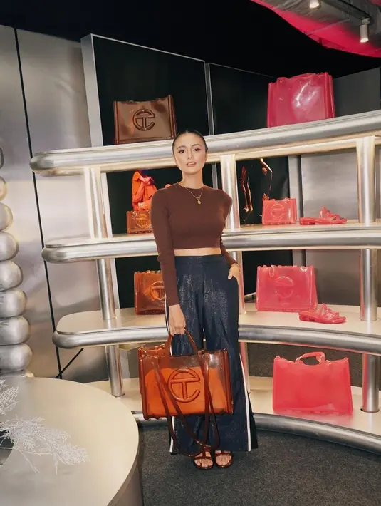 Amanda Rawles tampil glowing berpose di instalasi Melissa/Telfar. Cropped top cokelat dipadukannya dengan pants berkilau yang elegan. Ia juga terlihat menyempurnakan penampilannya dengan totebag cokelat dari koleksi kolaborasi ini. [Foto: Instagram/amandarawles]