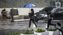 Pejalan kaki yang menggunakan payung saat hujan deras menyeberang jalan di kawasan Thamrin, Jakarta, Rabu (23/11/2022). Kepala Pelaksana Badan Penanggulangan Bencana Daerah (BPBD) DKI Jakarta Isnawa Adji mengimbau masyarakat untuk mengurangi aktivitas di luar rumah apabila Jakarta mengalami cuaca ekstrem. (Liputan6.com/Faizal Fanani)