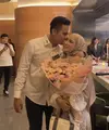 Ia pun membawa tas putih dengan strap hijau. Sementara sang suami mengenakan kemeja putih lengan panjang dipadukan celana hitam. [@chafrederica]