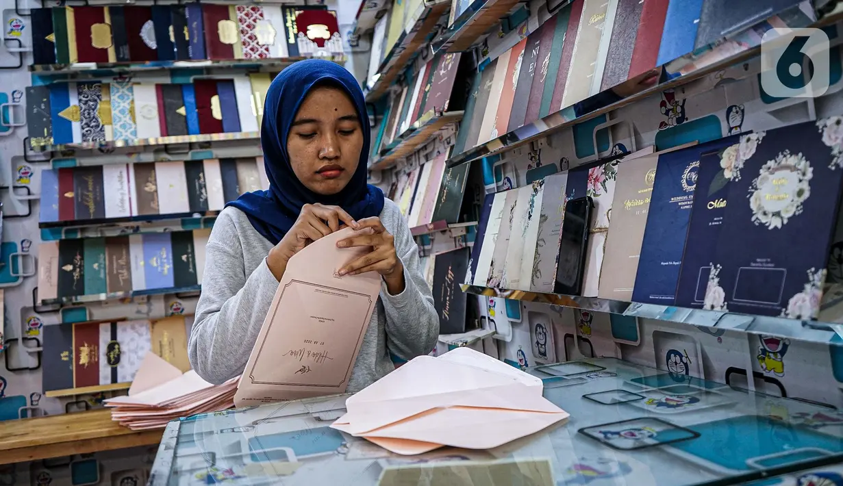 Aktivitas pedagang kertas undangan pernikahan di Pasar Tebet, Jakarta, Kamis (22/7/2020). Adanya larangan saat pandemi covid-19 untuk mengadakan acara yang bisa menimbulkan kerumunan, seperti pesta pernikahan, menyebabkan pendapatan usaha percetakan ini turun drastis. (Liputan6.com/Faizal Fanani)