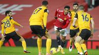 Penyerang Manchester United, Marcus Rashford, berusaha melewati empat pemain Wolverhampton Wanderers pada laga Liga Inggris di Stadion Old Trafford, Selasa (29/12/2020). Gol semata wayang Rashford menjadi penentu kemenangan Setan Merah atas Wolves. (Martin Rickett, Pool via AP)