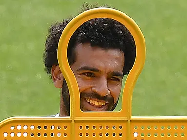 Gelandang Liverpool asal Mesir Mohamed Salah tersenyum saat mengikuti sesi pelatihan di stadion Anfield, Inggris (21/5). Liverpool akan bertanding melawan wakil Spanyol, Real Madrid pada babak Final Liga Champions. (AFP Photo/Paul Ellis)