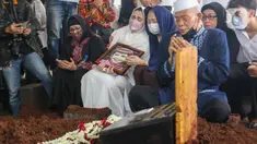 Nia Zulkarnaen, putri aktris senior Mieke Wijaya, menangis sambil memegang foto sang ibunda saat prosesi pemakaman di TPU Tanah Kusir, Jakarta, Rabu (4/5/2022). Mieke Wijaya meninggal dunia pada Selasa, 3 Mei 2022 di Jakarta. Ia meninggal dunia pada usia 82 tahun. (Liputan6.com/Herman Zakharia)
