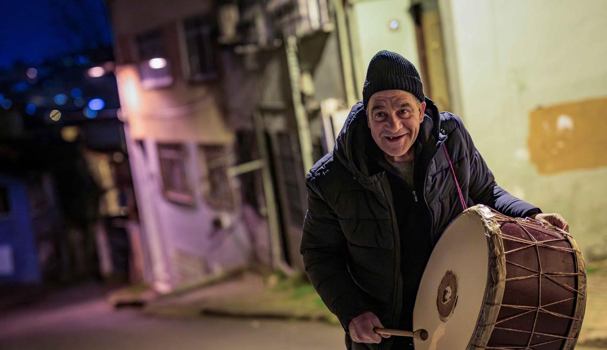 Mereka akan keluar memainkan drum dan menyanyikan lagu-lagu tradisional atau membaca puisi pendek tentang Ramadan. Tampak dalam foto, penabuh gendang Turki, Hakan Ozbingol, memainkan gendang dan menyanyikan lagu-lagu tradisional di jalanan Istanbul, untuk membangunkan umat Muslim untuk sahur, yaitu makan malam Ramadan, pada 24 Februari 2026. (Yasin AKGUL/AFP)