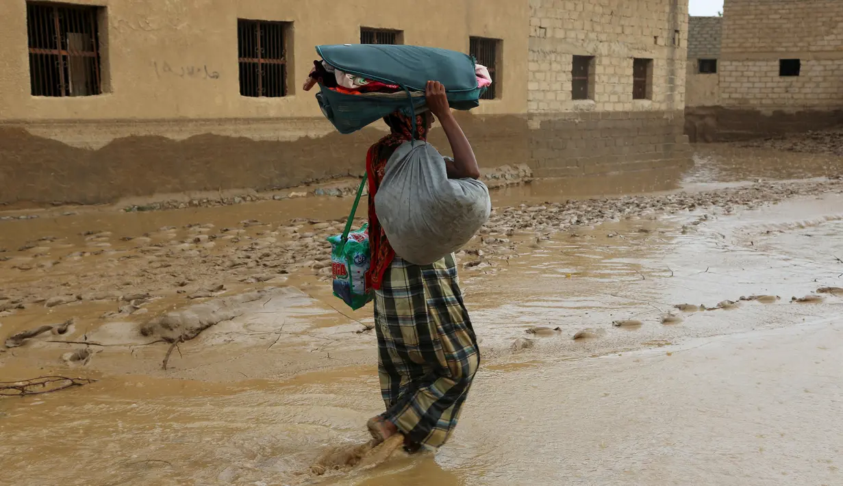 Seorang pria membawa barang miliknya melintasi banjir setelah hujan deras melanda sebuah desa di provinsi Laut Merah Yaman, Houdieda, Jumat,  15 April 2016. (REUTERS/Abdul Jabbar Zeyad)