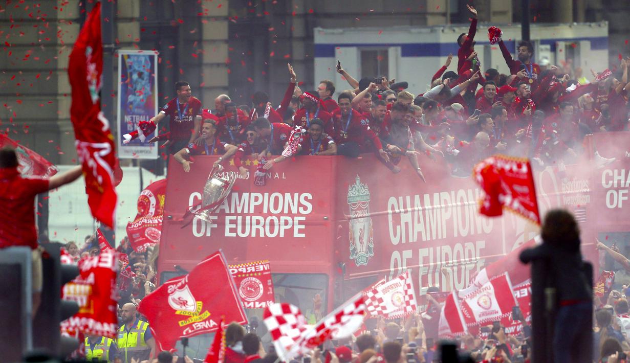 Para pemain Liverpool menyapa fans saat parade juara Liga Champions 2019 di Liverpool, Minggu (2/6). Ribuan fans tumpah ruah di jalanan untuk merayakan keberhasilan pemain membawa pulang trofi Si Kuping Besar ke kota Liverpool. (AP/Richard Sellers)