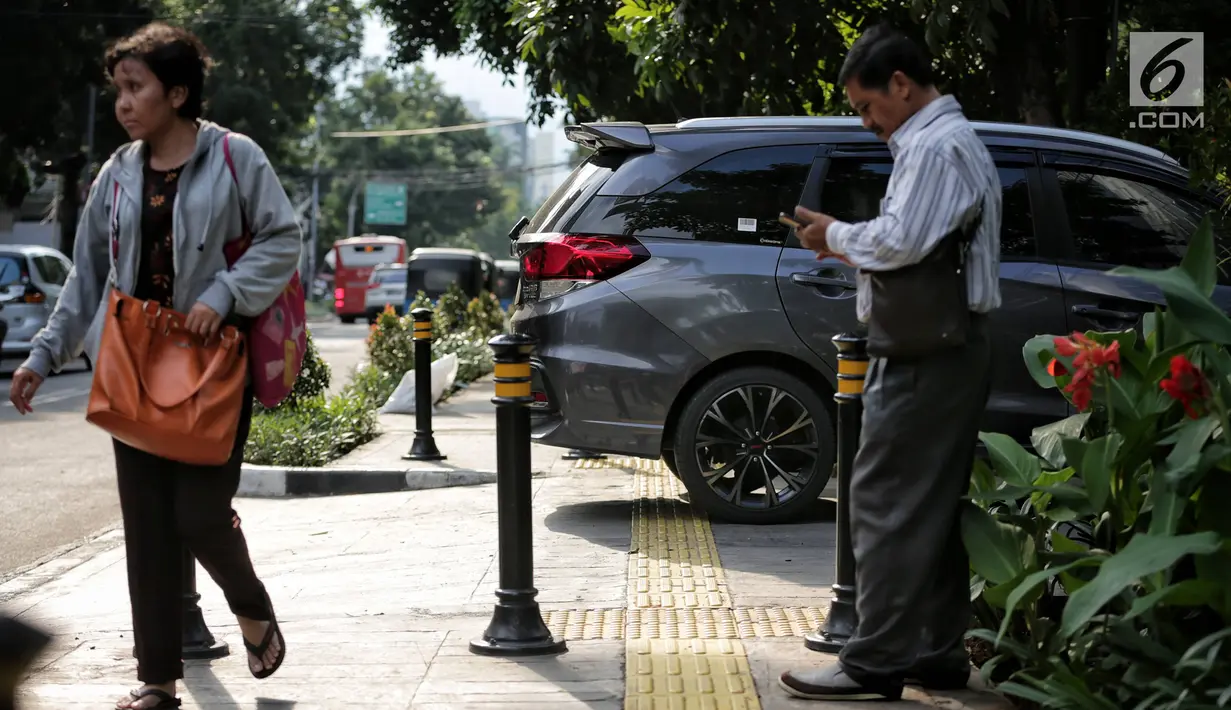 Sebuah mobil menghalangi jalur difabel trotoar di kawasan Sarinah, Jakarta, Rabu (6/1). Kondisi trotoar yang tidak steril ini menyulitkan pejalan kaki, terutama difabel saat melintas. (Liputan6.com/Faizal Fanani)