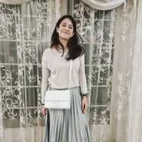 Dian Sastro tampil kasual dengan atasan lengan panjang wsrna nude, dipadukan skirt panjang plisket warna abu-abu. Ia puj mengenakan heels dsn sling bag putihnya. @therealdisastr
