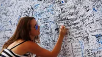 Meski telah penuh dengan tulisan dan tanda tangan, keinginan untuk ikut serta memberikan tulisan empati terus berdatangan (REUTERS/Edgar Su)