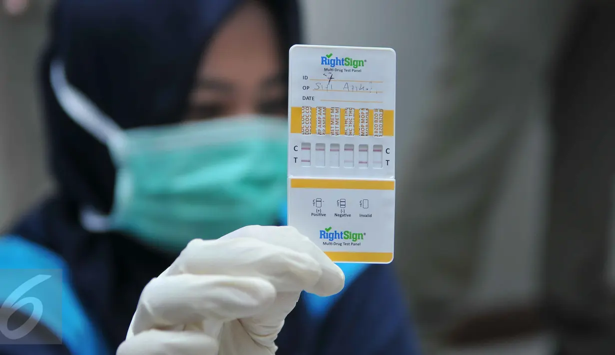Petugas BNN menunjukkan hasil tes urine penghuni kos-kosan di Jalan Taman Sari Raya No 60-62, Jakarta (1/10). Dari razia ini, delapan orang terdiri dari tujuh wanita dan satu pria diamankan karena positif mengonsumsi narkoba. (Liputan6.com/Gempur M Surya)