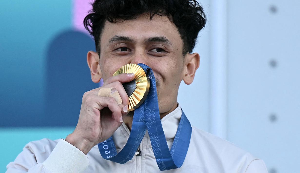 <p>Atlet panjat tebing Indonesia, Veddriq Leonardo mencium medali emasnya saat di atas podium cabang olahraga panjat tebing nomor speed Olimpiade Paris 2024 di Le Bourget Sport Climbing Venue, Paris, Prancis, Kamis (08/08/2024). (AFP/Jonathan Nackstrand)</p>