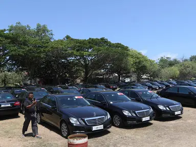 Seorang supir berjalan di antara mobil Toyota Camry dan Mercy E200 di Lapangan Lagoon Bali, Nusa Dua, Selasa (9/10). Sebanyak 865 unit kendaraan disiapkan untuk mengangkut delegasi Pertemuan Tahunan IMF-World Bank di Bali. (Liputan6.com/Angga Yuniar)