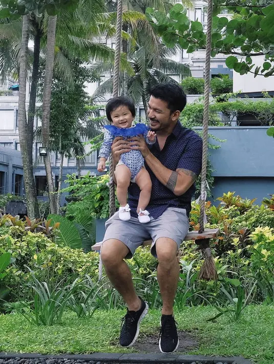 Seperti di foto ini Rio terlihat sedang bermain ayunan bersama dengan Salma, si bayi mungil yang menggemaskan. Bapak dan anak ini kompak dengan baju berwarna birunya. (Instagram/riodewanto)