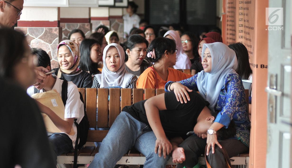 Orangtua murid menunggu antrean pengambilan nomor token PPDB DKI Jalur Zonasi di SMA Negeri 21, Jakarta, Senin (24/6/2019). Pendaftaran PPDB DKI Jakarta Jalur Zonasi SMP-SMA dibuka pada 24-26 Juni 2019 mulai pukul 08.00-16.00 WIB. (merdeka.com/Iqbal Nugroho)
