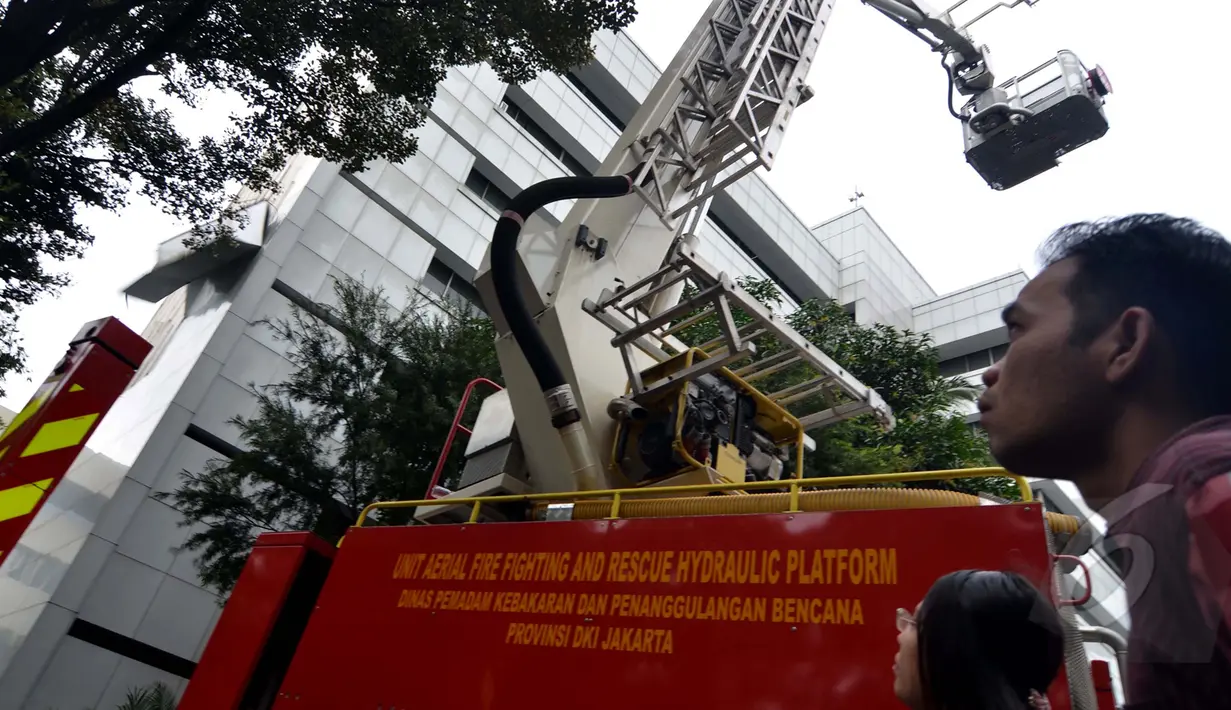 Petugas pemadam kebakaran dan teknisi konstruksi mengevakuasi pelapis dinding gedung Sekretariat Jenderal DPR RI yang roboh ditiup angin kencang di Kompleks Parlemen, Jakarta, Jumat (24/04/2015). (Liputan6.com/Andrian M Tunay)