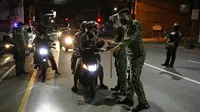 Polisi memeriksa pengendara sepeda motor saat jam malam untuk mencegah penyebaran COVID-19 di Metro Manila, Filipina, Senin (15/3/2021). Kementerian Kesehatan Filipina melaporkan lonjakan kasus COVID-19 selama lebih dari seminggu. (AP Photo/Aaron Favila)