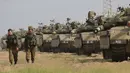 Tentara Israel berjalan melewati tank di dekat perbatasan Gaza-Israel, Jumat (19/10). Delegasi Mesir telah berkomunikasi dengan para pemimpin Israel untuk mengatasi ketegangan yang terjadi. (AP Photo/Ariel Schalit)