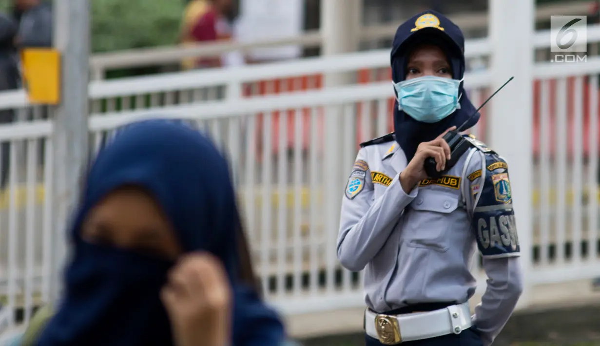 Petugas Dinas Perhubungan mengenakan masker saat bertugas di Jakarta, Kamis (4/7/2019). Warga disarankan menggunakan masker saat berangkat kerja atau beraktivitas di luar ruangan akibat kualitas udara Jakarta yang buruk. (merdeka.com/Imam Buhori)