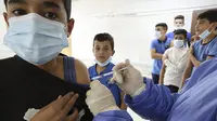 Pegawai Kementerian Kesehatan Palestina memberikan suntikan vaksin COVID-19 Pfizer/BioNTech kepada siswa sekolah berusia 12 tahun ke atas di Desa Dura, Hebron, Palestina, 24 November 2021. Total kasus COVID-19 di Palestina mencapai 428.857, meninggal 4.520, sembuh 421.669. (HAZEM BADER/AFP)