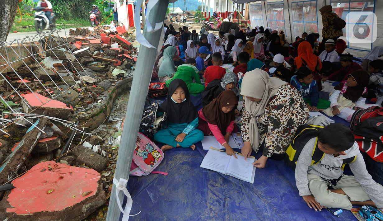 Murid-murid korban gempa belajar pada tenda darurat yang dibangun di halaman sekolah di SDN Gintung, Mangunkerta, Cianjur, Jumat (23/12/2022). Lebih dari sebulan sejak musibah gempa bumi 5,2 SR sejumlah murid sekolah di Cianjur masih belajar pada tenda darurat. (merdeka.com/Arie Basuki)