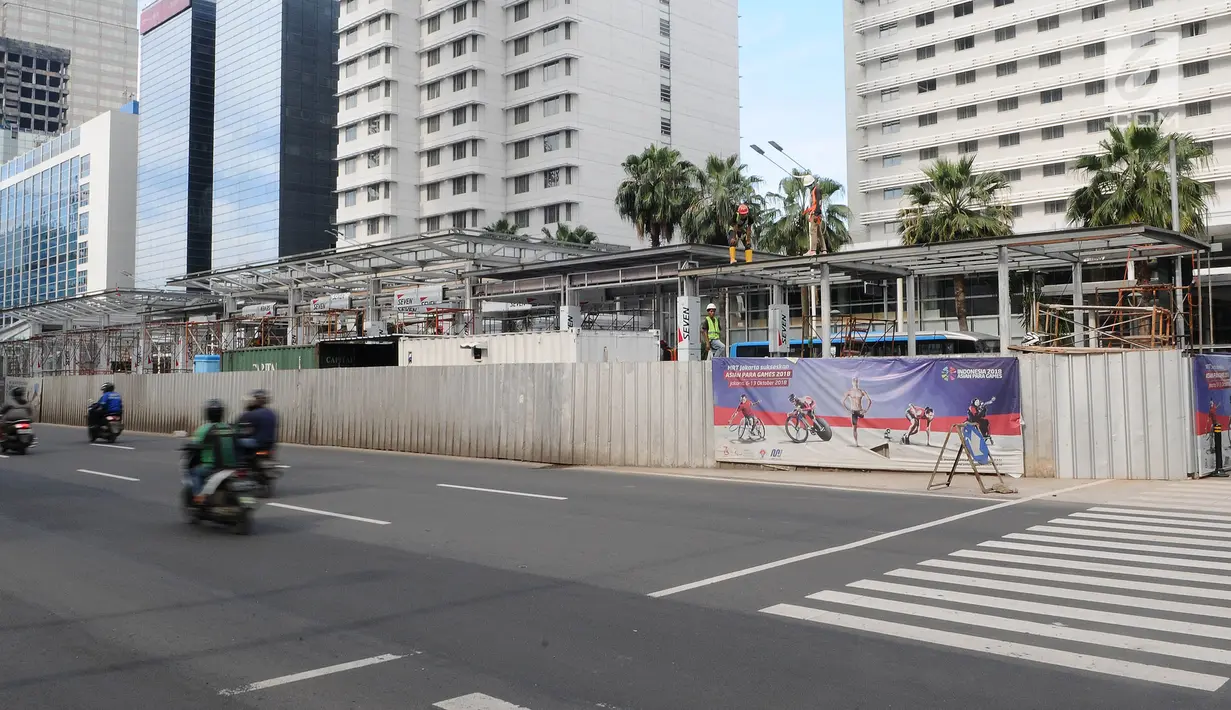Pengendara sepeda motor melintas saat pekerja menyelesaikan proyek pembangunan Halte Transjakarta Bundaran HI di Jakarta, Sabtu (9/3). Halte Transjakarta ini akan menjadi yang pertama terintegrasi dengan stasiun MRT Jakarta. (Liputan6.com/Herman Zakharia)