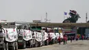 Orang-orang berjalan melewati truk-truk yang dimuat dengan bantuan untuk Gaza, menunggu di sisi Mesir dari pos perbatasan Rafah pada 18 Agustus 2025. (Khaled DESOUKI/AFP)