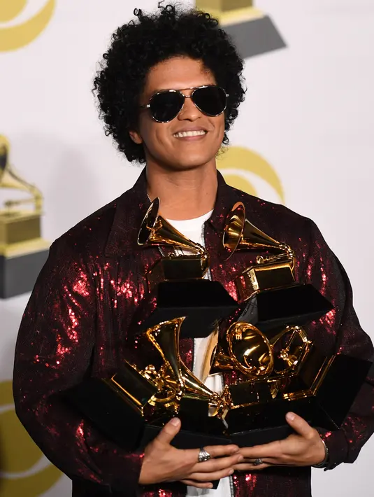 Penyanyi R&B, Bruno Mars berpose dengan trofi Grammy Awards 2018 di New York City, Minggu (28/1). Menang di seluruh kategori yang menominasikan dirinya, Bruno menjadi artis yang memborong Grammy paling banyak malam itu. (AFP PHOTO/Don EMMERT)
