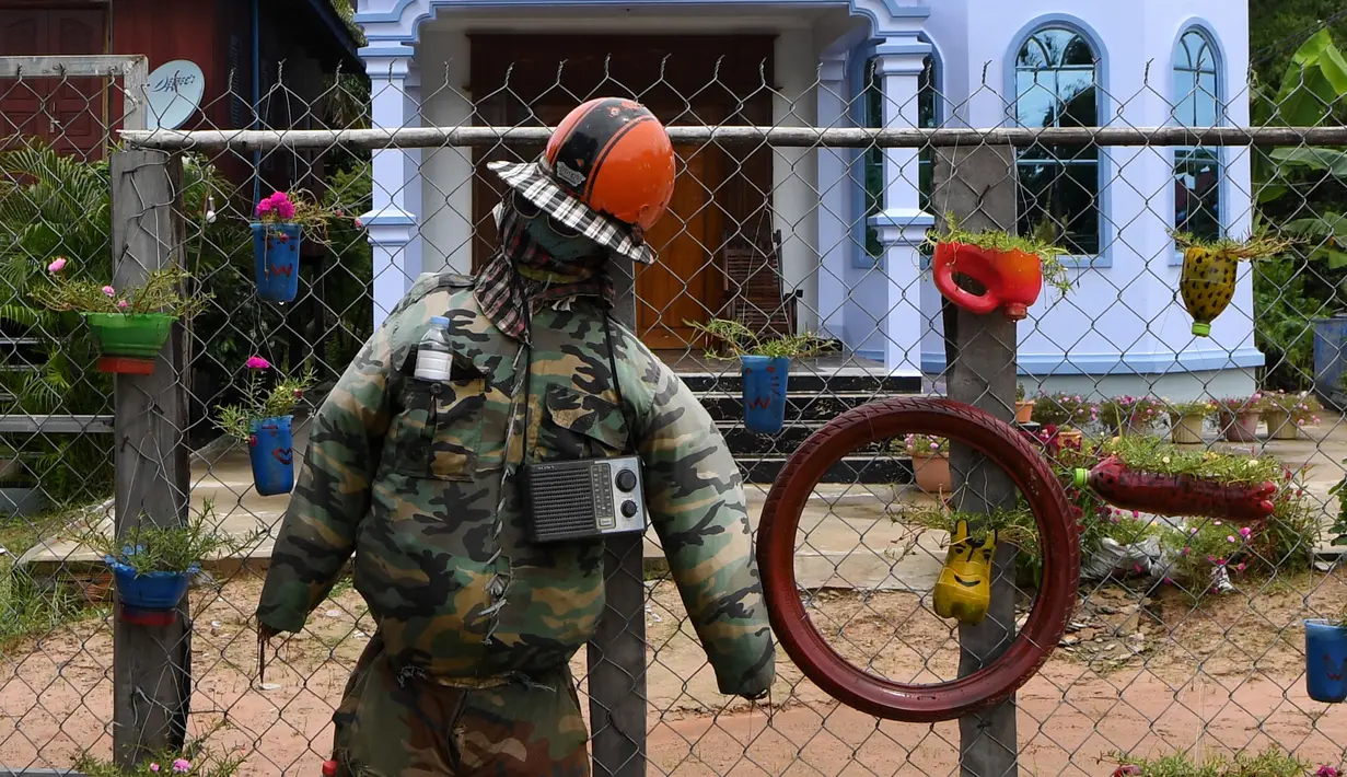 Orang-orangan sawah diikat ke pagar di depan sebuah rumah di provinsi Kampong Cham, Kamboja, 11 Oktober 2020. Para petani di desa itu menggunakan orang-orangan sawah atau disebut juga Tim Mong untuk menangkal virus corona  Covid-19 berdasarkan kepercayaan yang mereka yakini. (TANG CHHIN Sothy/AFP)