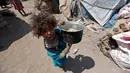 Seorang anak membawa panci saat berada dekat tenda tempat tinggalnya di kamp pengungsian di Sanaa, Yaman, (15/4). Mereka mengungsi akibat konflik di negaranya yang belum terseleasikan (AFP Photo / Mohammed Huwais)