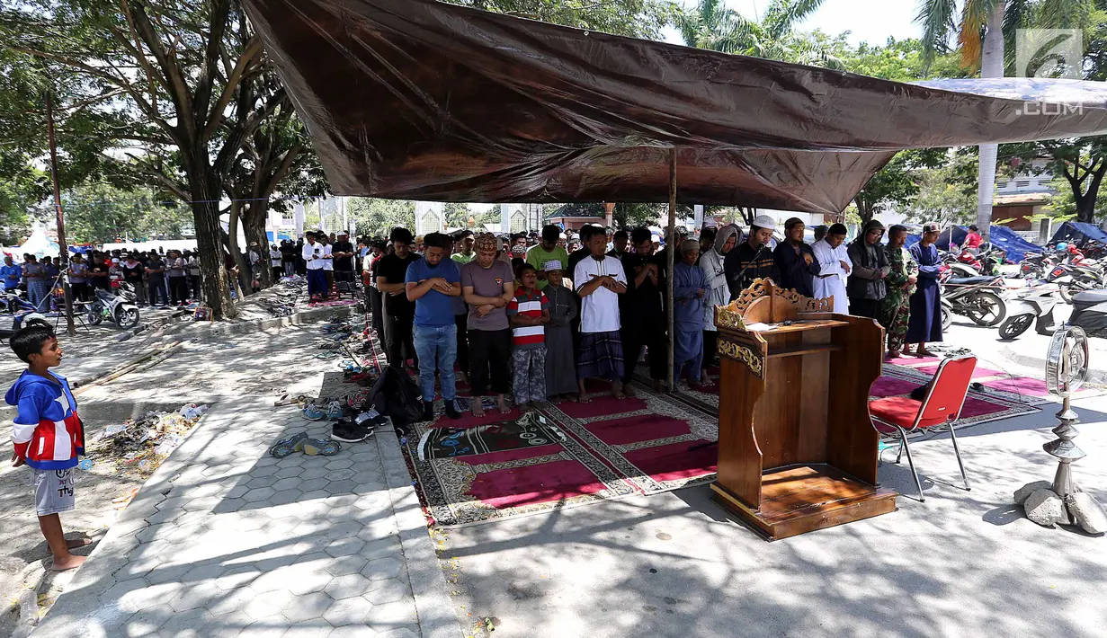 Ratusan pengungsi menjalankan salat Jumat pascagempa dan tsunami di Lapangan Masjid Agung Daru Salam, Palu, Jumat (5/10). Sebuah terpal cokelat menjadi atap melindungi imam salat dari panas matahari. (Liputan6.com/Fery Pradolo)