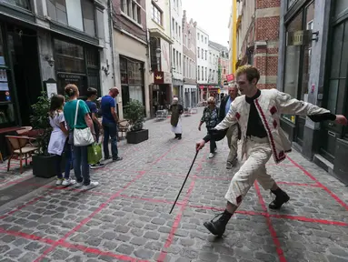 Seorang seniman memainkan permainan dalam garis persegi (grid game) dengan pelintas di Royal Gallery of Saint Hubert di Brussel, Belgia (15/7/2020). Permainan ini dirancang agar orang menghormati aturan jaga jarak sosial selama pandemi COVID-19. (Xinhua/Zheng Huansong)