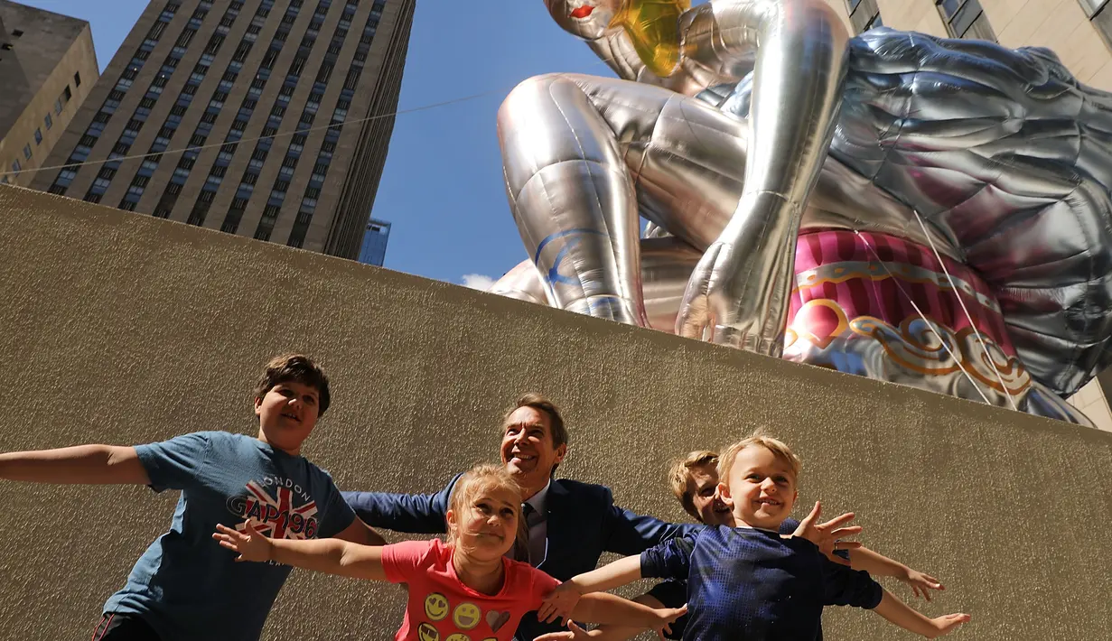 Pengunjung berpose di dekat balon penari balet karya seniman Jeff Koons, di Rockefeller Center, New York City, AS, Jumat (12/5). Keberadaan balon penari balet menjadi ajang foto pengunjung Rockefeller Center. (Spencer Platt / Getty Images / AFP)