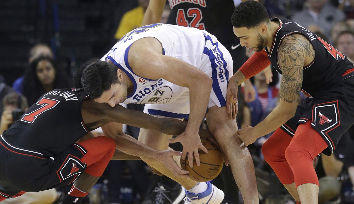 Pemain Golden State Warriors, Zaza Pachulia (tengah) berusaha keluar dari kepungan pemain Chicago Bulls pada laga NBA basketball game di Oracle Arena, Oakland, (24/11/2017). Warriors menang 143-94. (AP/Jeff Chiu)
