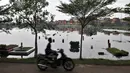 Pengendara sepeda motor melintasi ratusan makam yang terendam banjir di TPU Semper, Jakarta, Selasa (4/12).  (Merdeka.com/Iqbal S. Nugroho)