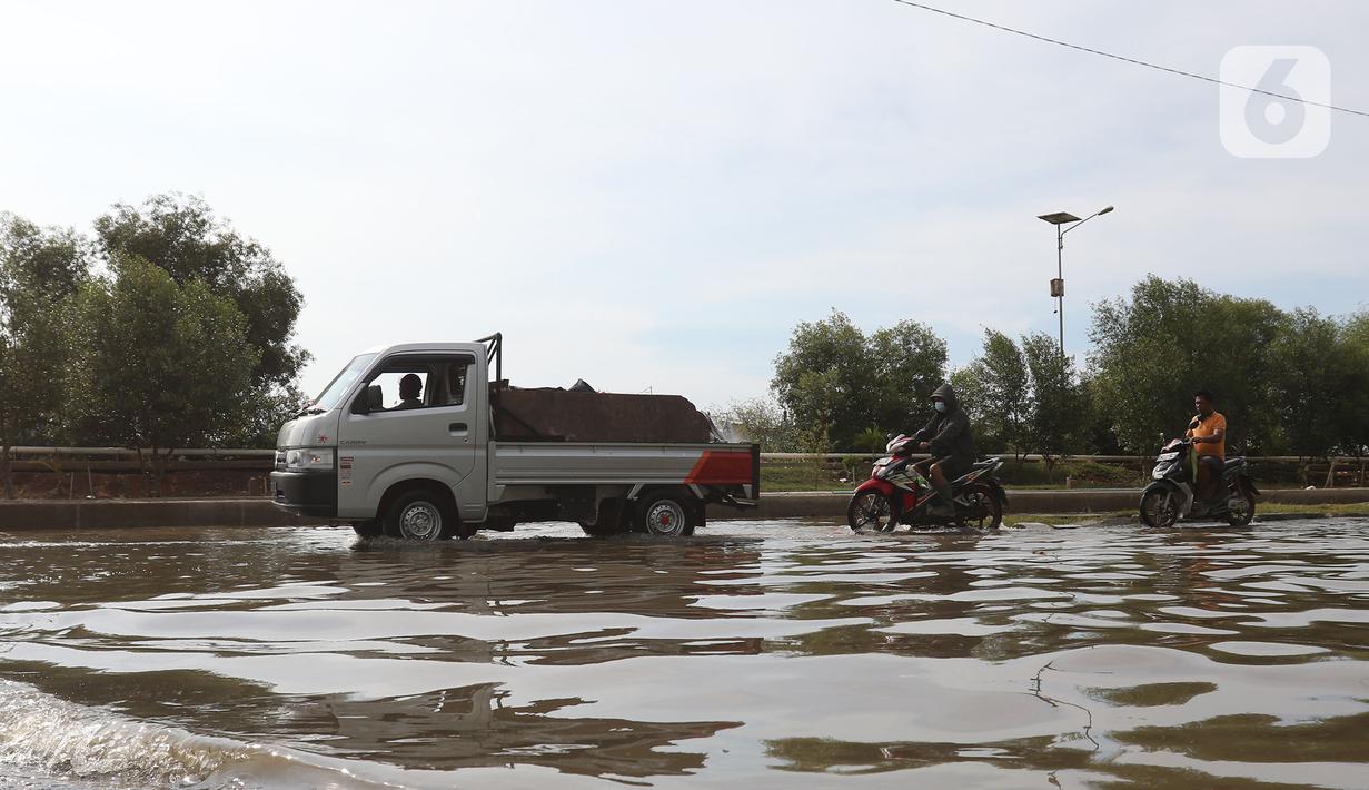 Pengendara kendaraan bermotor melintasi banjir rob di kawasan Pelabuhan Perikanan Samudera Nizam Zachman, Muara Baru, Jakarta, Sabtu (6/11/2021). Banjir rob tersebut disebabkan karena naiknya permukaan air laut. (Liputan6.com/Herman Zakharia)
