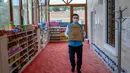 Imam masjid Dedeman, Abdulsamet Cakir membawa barang-barang di pintu masjid di distrik Sariyer, Istanbul pada 21 April 2020. Jelang Ramadan, masjid itu membuka supermarket gratis yang menyediakan kebutuhan sehari-hari secara gratis untuk warga membutuhkan yang terdampak Corona. (Bulent Kilic/AFP)