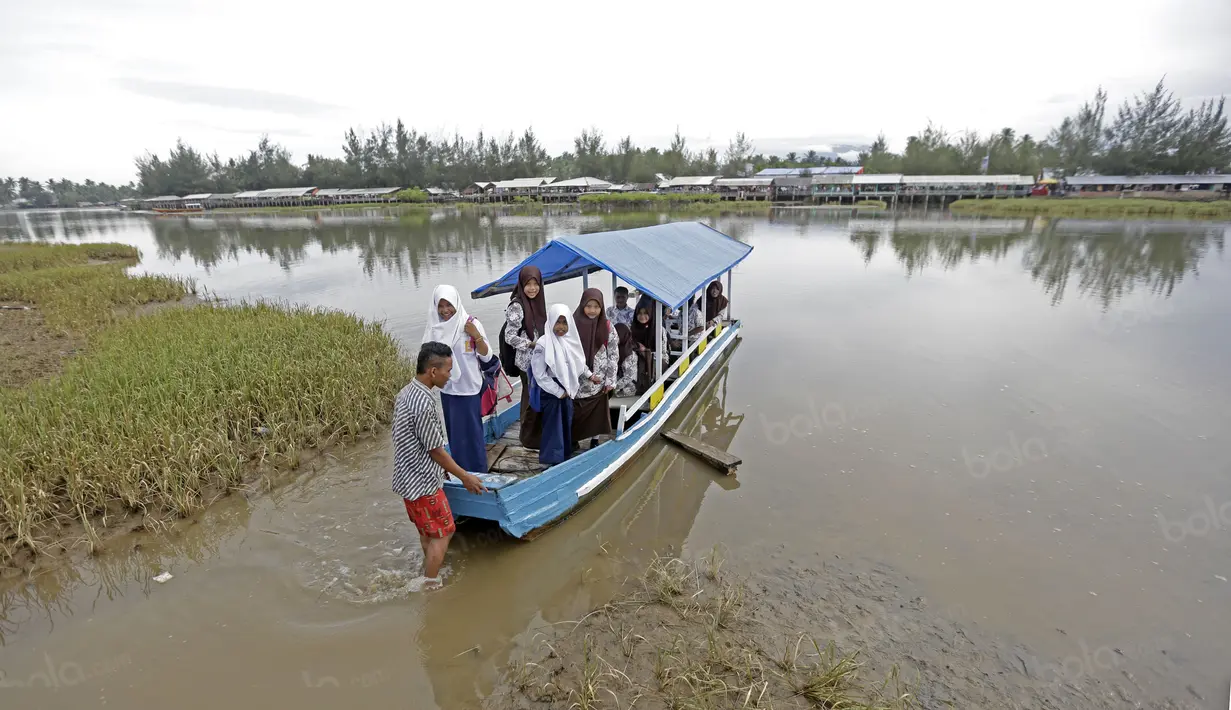 Anak-anak menggunakan perahu menuju sekolahnya dekat garis start Tour de Singkarak 2016 di Pariaman, Sumatera Barat, (10/8/2016). (Bola.com/Nicklas Hanoatubun)