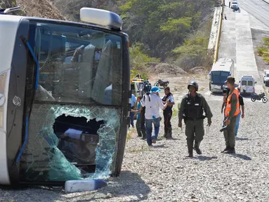 Petugas berdiri di dekat bus yang terbalik di jalan raya Caracas-La Guaira di Caracas, Venezuela, Rabu (10/2). Bus yang mengangkut pemain tim sepak bola Argentina Huracan itu kecelakaan saat menuju Bandara Internasional Simon Bolivar. (AFP/FEDERICO PARRA)