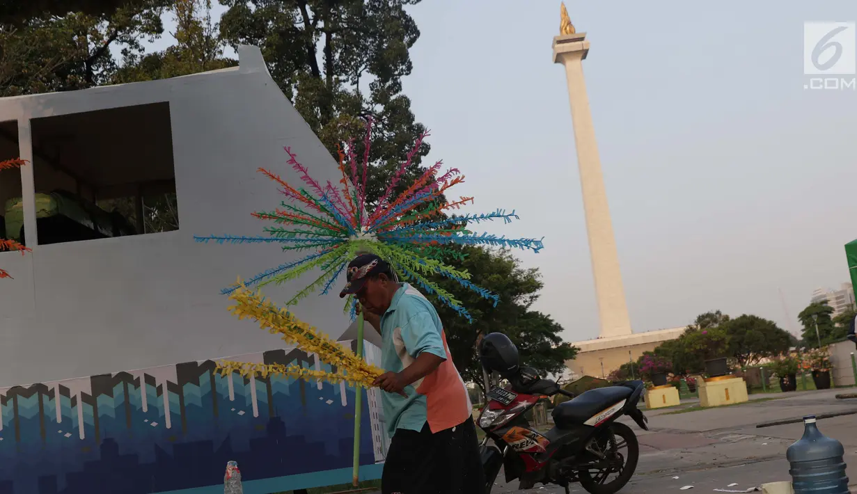 Pekerja menyelesaikan pembuatan kembang hiasan untuk diletakkan di atas kendaraan hias di kawasan Monas, Jakarta, Jumat (28/6/2019). Kendaraan hias tersebut dipersiapkan untuk Jakarnaval 2019 yang menjadi  perayaan HUT ke-492 DKI Jakarta, Minggu (30/6). (Liputan6.com/Helmi Fithriansyah)