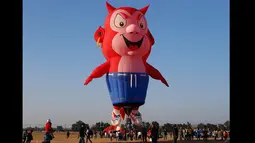 Penonton mengambil gambar dan menonton Burnie balon udara Little Devil saat lepas landas selama Filipina International Hot Air Balloon Fiesta, Manila, Kamis (12/2/2015). (Reuters / Erik De Castro)