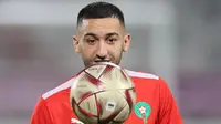 Gelandang Maroko, Hakim Ziyech menatap bola saat ia mengambil bagian dalam sesi latihan di Stadion Al Duhail SC di Doha pada 13 Desember 2022. Maroko akan bertanding melawan Prancis dalam pertandingan semifinal Piala Dunia 2022 di Stadion Al Bayt, Al Khor, Kamis (15/12/2022) pukul 02.00 WIB. (AFP/Karim Jaafar)