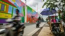 Pengendara motor melintasi mural yang dibuat di Flyover Gaplek, Tangerang Selatan, Rabu (10/3/2021). Konsep muralnya adalah "Tangsel Membangun". (Liputan6.com/Faizal Fanani)