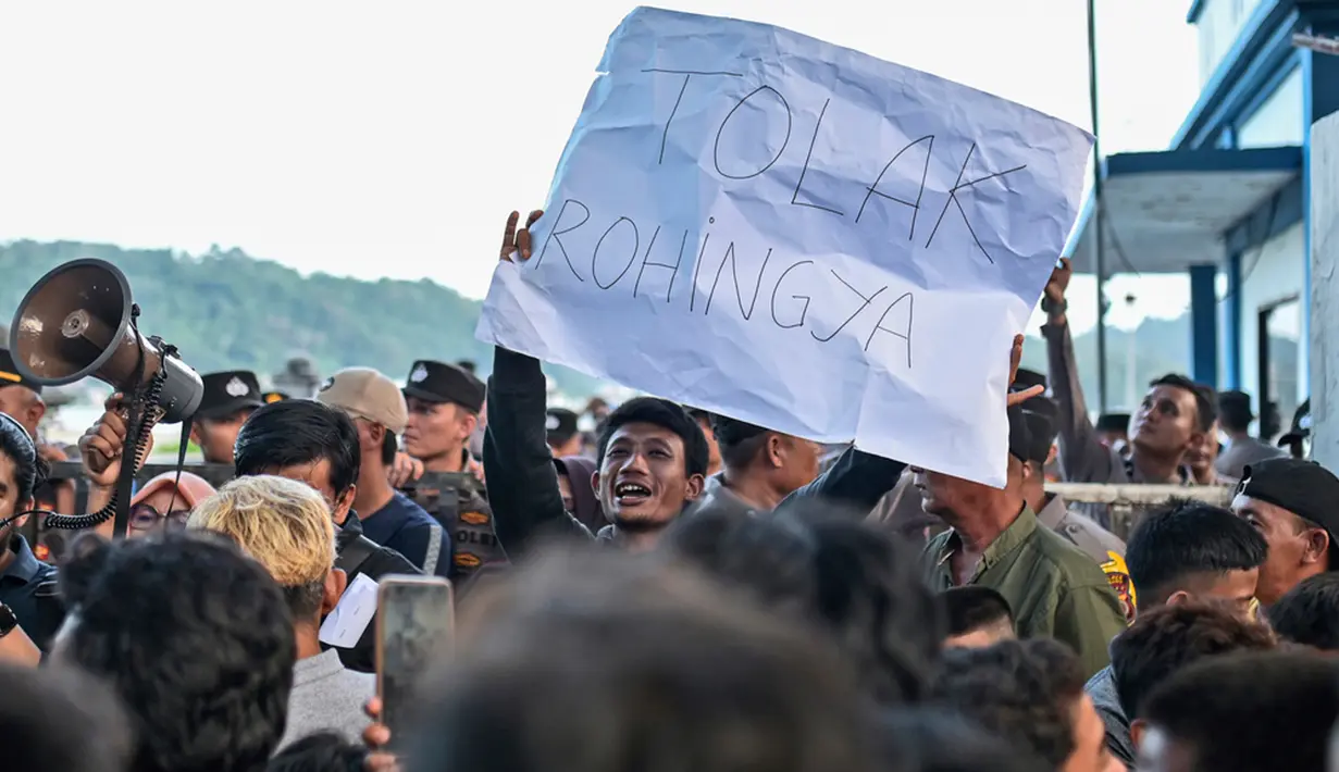Seorang pengunjuk rasa membawa poster bertuliskan "Tolak Rohingya". (AP Photo/Reza Saifullah)