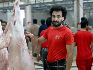 Mohammad Ibraheem saat memotong daging di sebuah rumah jagal hewan di hari ketiga Idul Adha di Kota Kuwait (13/8/2019). Pria 27 tahun ini mendadak terkenal karena kemiripan wajahnya dengan pemain Liverpool asal Mesir, Mohamed Salah. (AFP Photo/Yasser Al-Zayyat)
