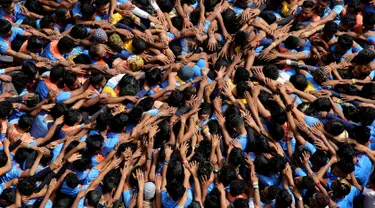 Pemuda India membentuk piramida manusia dalam perayaan Festival Janmashtami di Mumbai, Senin (3/9). Piramida manusia itu dibentuk untuk memecahkan pot berisikan susu yang menggantung di langit-langit rumah supaya bisa diambil isinya. (AP/Rafiq Maqbool)