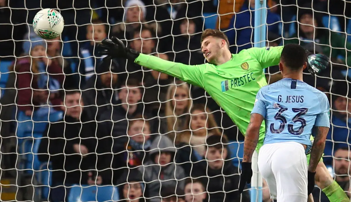 Penyerang Manchester City, Gabriel Jesus mencetak gol yang gagal dihadang kiper Burton Albion, Bradley Collins pada laga leg pertama semifinal Piala Liga Inggris di Stadion Etihad, Kamis (10/1). Manchester City menang telak 9-0. (AP/Dave Thompson)