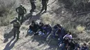 Petugas menangkap imigran Meksiko yang berusaha menyeberangi perbatasan AS-Meksiko di McAllen, Texas (3/1). Ribuan imigran masuk secara ilegal melintasi perbatasan mencari suaka di AS jelang pelantikan AS Donald Trump. (AFP Photo/John Moore/Getty Images)